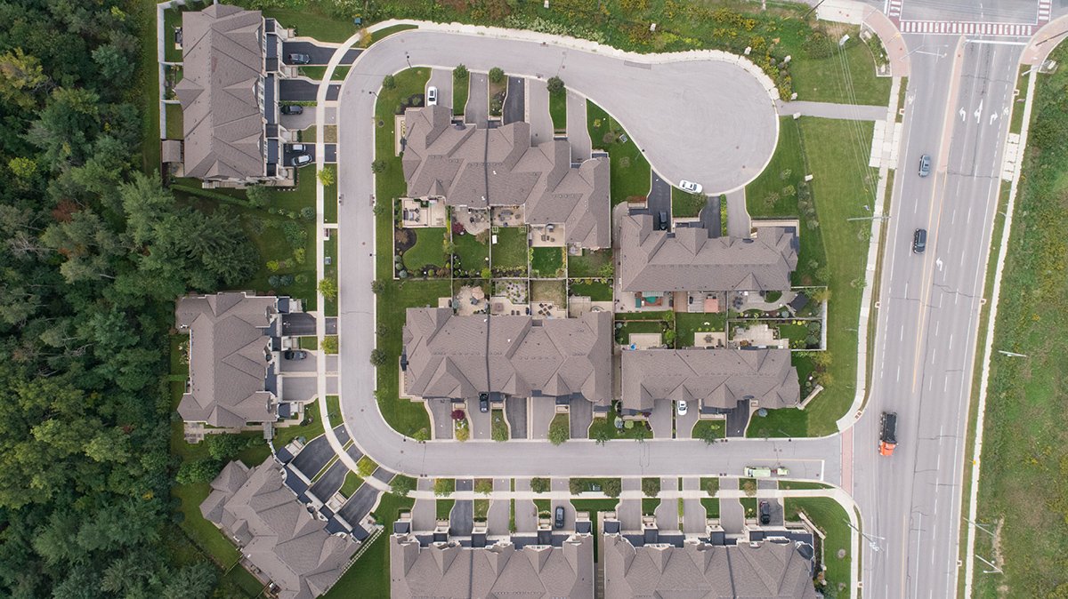 Aerial view of an Acorn Developments neighbourhood with homes around a cul-de-sac bordered by trees and a roadway